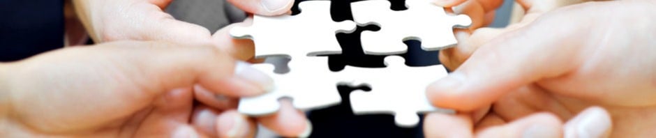 Four hands holding puzzle pieces